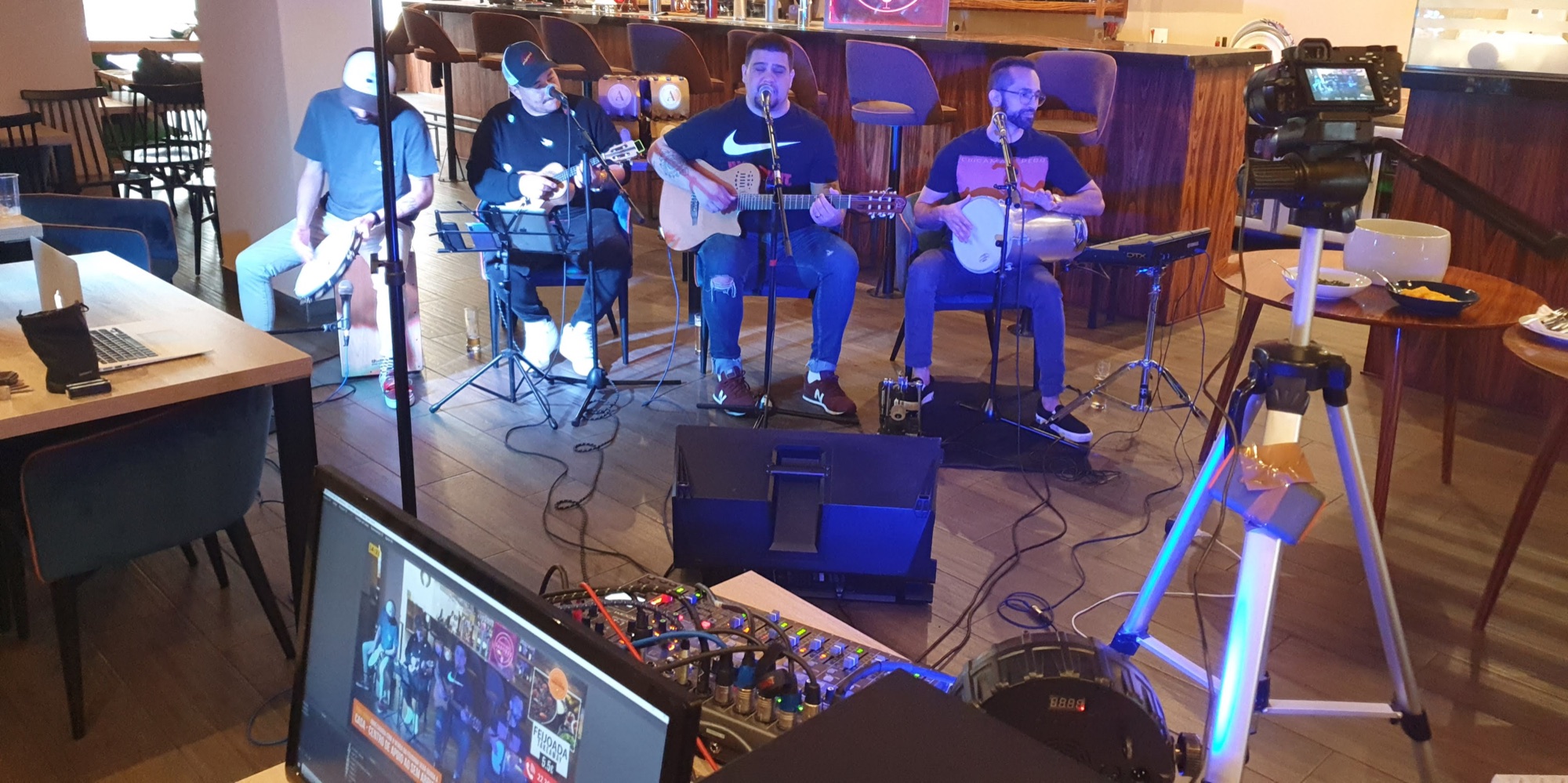 Banda sendo gravada com câmera, mesa de áudio e monitor